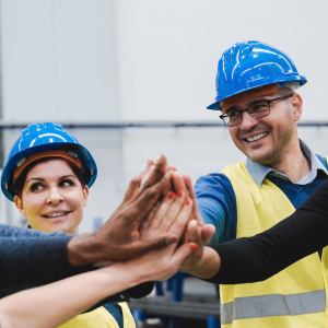 Happy multiracial engineer stacking hands while working at robotics warehouse - Focus on center man face